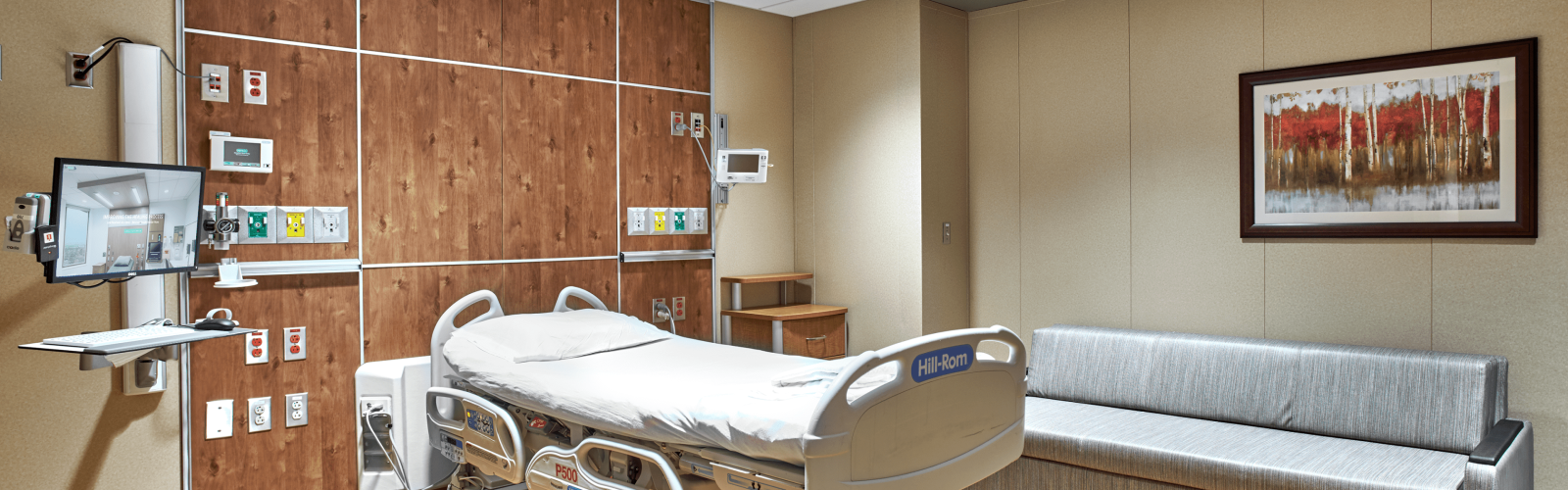 Hospital patient room with wall-mounted TV on articulating headwall arm and telehealth AV equipment