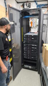 Josh standing in front of Turn key IT office build out installation of network and infrastructure rack including cables, server and switches.